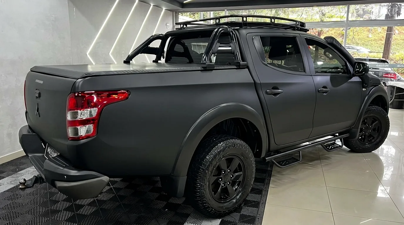 Mitsubishi L200 envelopada em preto fosco, vista lateral traseira